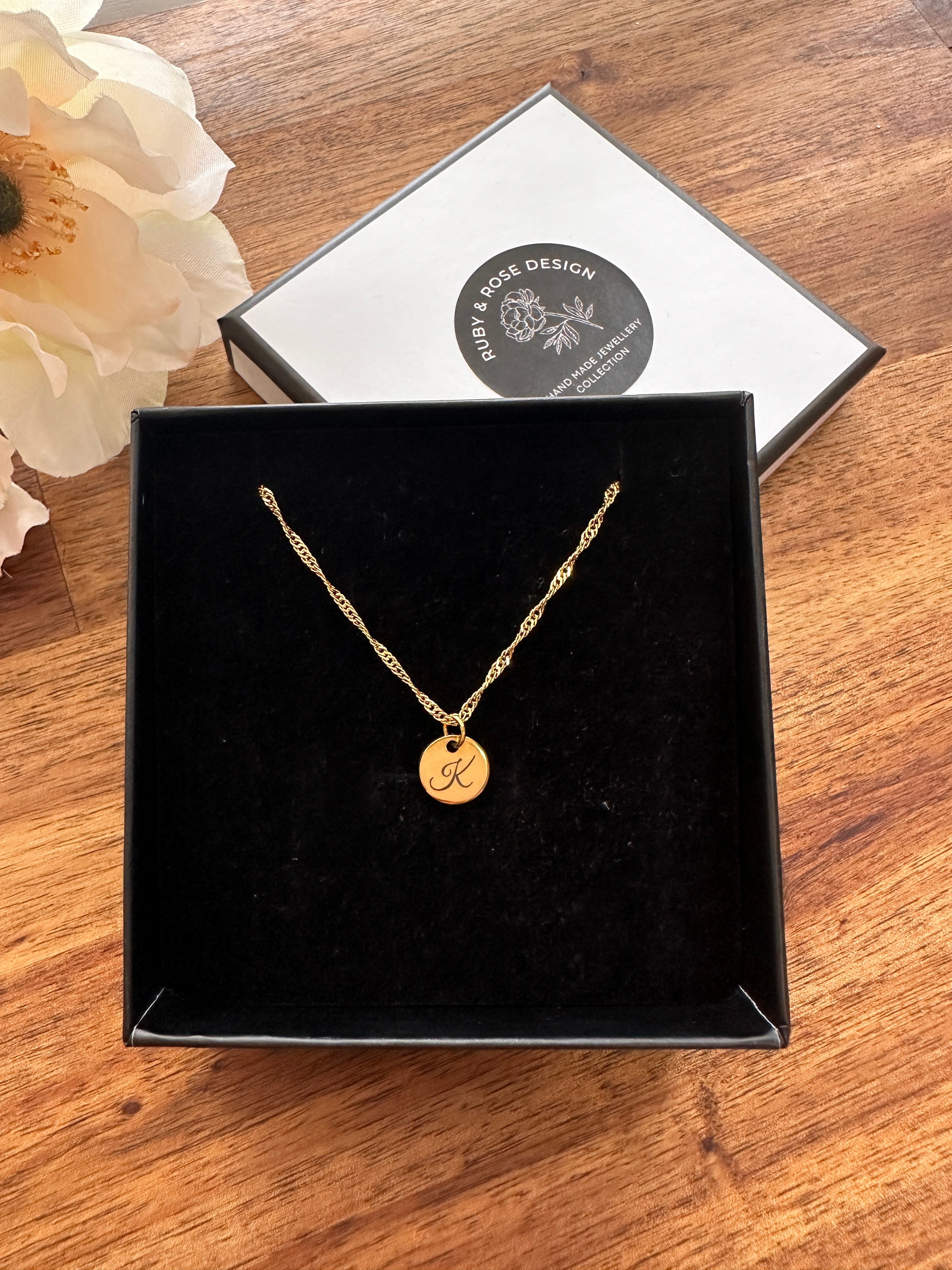 Gold necklace with a round pendant in a black box on a wooden surface